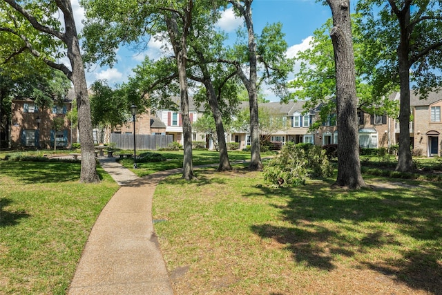 view of community with a lawn, fence, and a residential view