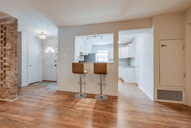 foyer entrance featuring light wood-style floors, visible vents, baseboards, and track lighting