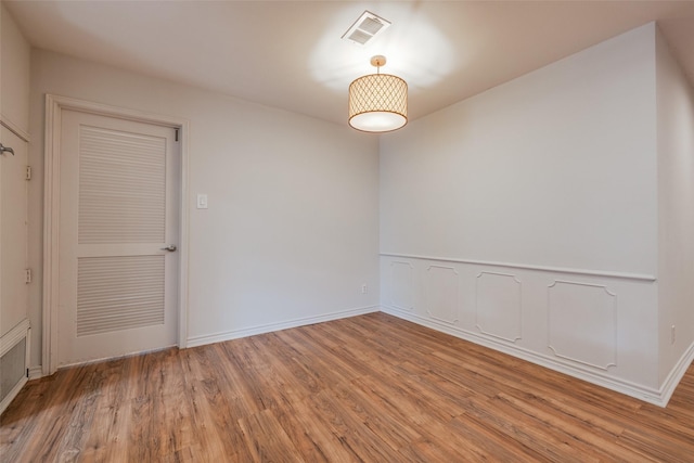 empty room featuring baseboards, light wood finished floors, and visible vents
