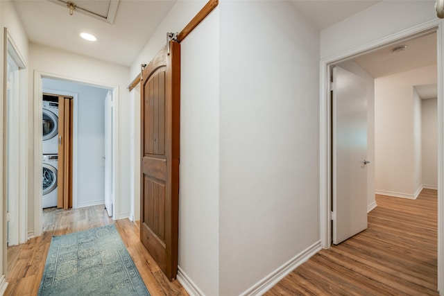 corridor with recessed lighting, light wood-style flooring, stacked washer and dryer, and baseboards