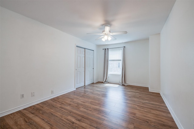 unfurnished bedroom with baseboards, wood finished floors, a closet, and ceiling fan