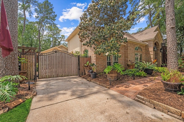 exterior space featuring concrete driveway, a gate, and brick siding