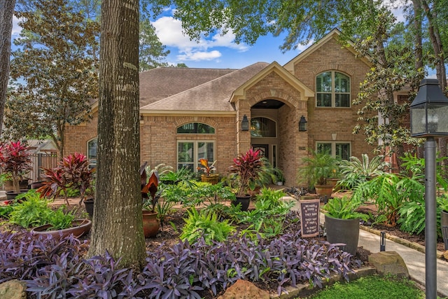 view of front of property with brick siding and roof with shingles