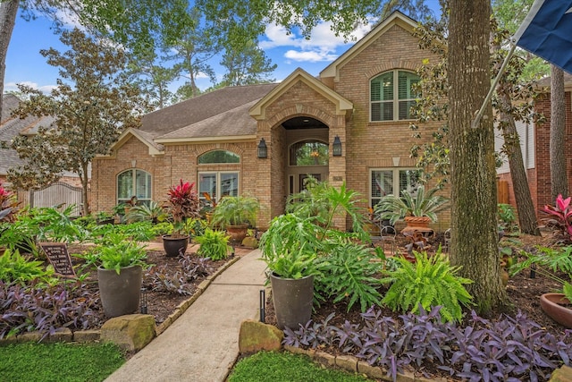 traditional home with roof with shingles, fence, and brick siding