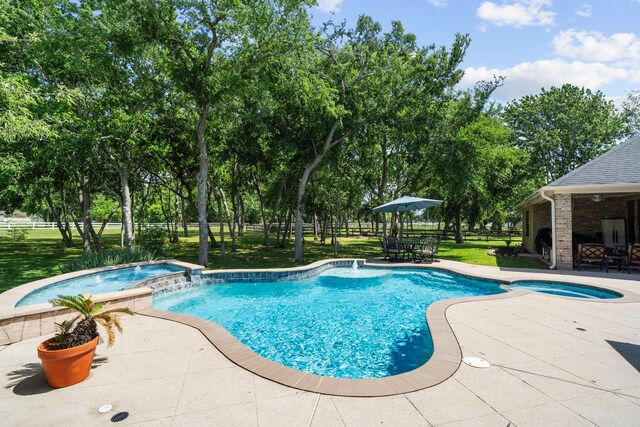 view of swimming pool with fence, a patio, a yard, a pool with connected hot tub, and outdoor dining area