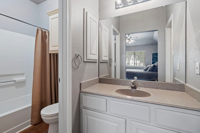 ensuite bathroom with toilet, a ceiling fan, vanity, and a textured wall