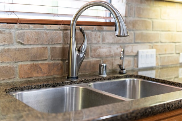 interior details featuring tasteful backsplash, dark stone counters, and a sink