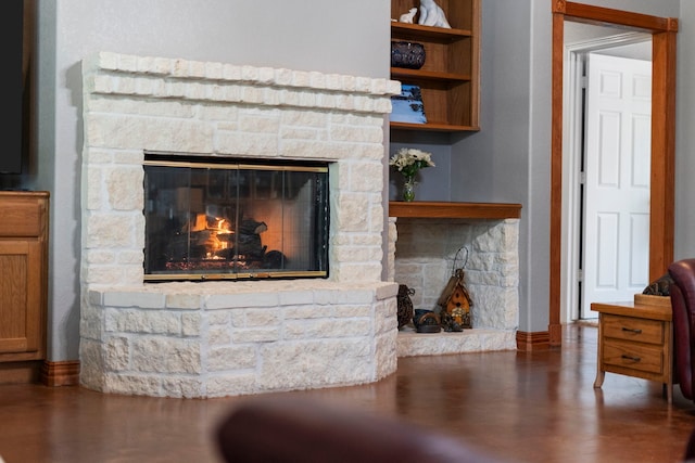 living area featuring a stone fireplace and baseboards