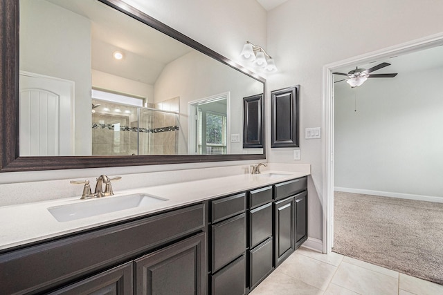 full bathroom featuring a tile shower, a sink, double vanity, a ceiling fan, and vaulted ceiling