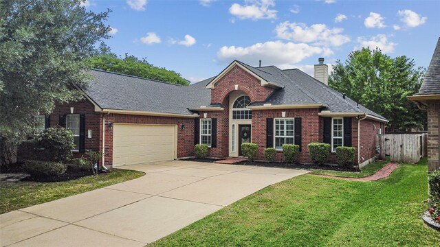 view of front facade featuring a shingled roof, brick siding, a front yard, and concrete driveway