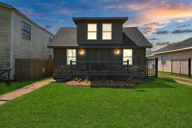 back of property featuring fence, a shingled roof, a yard, and a deck