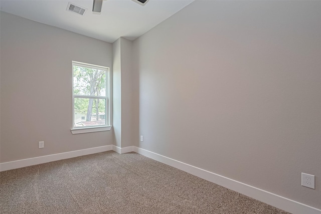 carpeted spare room with visible vents, baseboards, and ceiling fan
