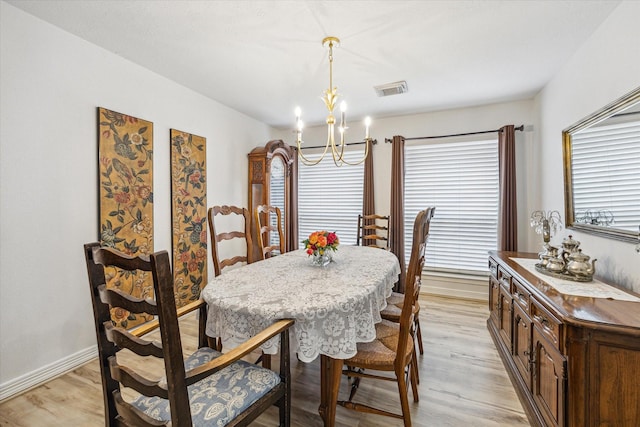dining space with a wealth of natural light, a notable chandelier, light wood finished floors, and visible vents
