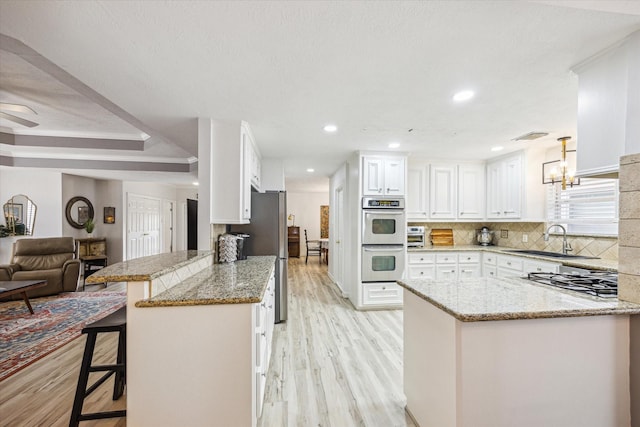 1807 Emerald Green Dr, Houston, TX 77094 - kitchen featuring a peninsula, stainless steel appliances, a sink, light wood finished floors, and recessed lighting