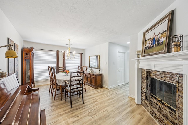 1807 Emerald Green Dr, Houston, TX 77094 - dining space with a chandelier, a textured ceiling, light wood-style floors, a fireplace, and baseboards