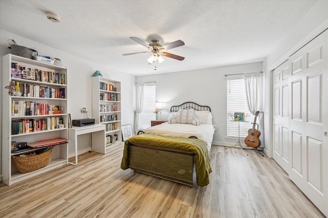 bedroom featuring wood finished floors, a closet, a ceiling fan, and multiple windows