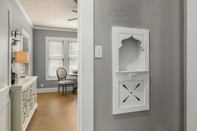 hallway with baseboards, wood finished floors, and ornamental molding