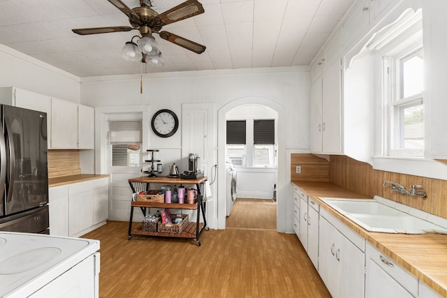 kitchen with a ceiling fan, a sink, freestanding refrigerator, white range with electric cooktop, and light wood-style flooring