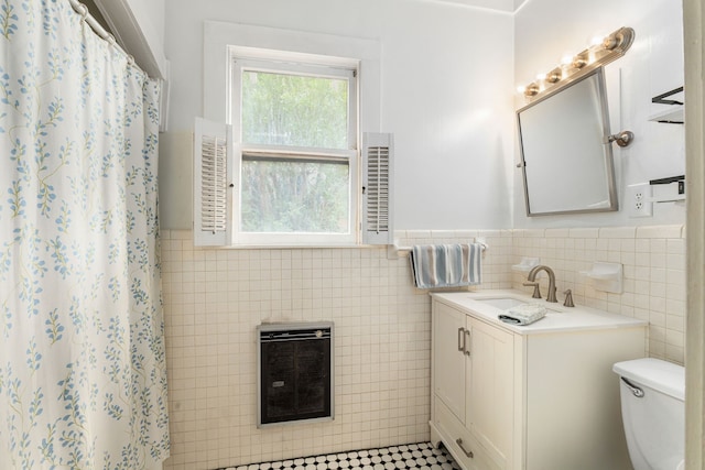 full bath featuring tile walls, heating unit, wainscoting, and toilet
