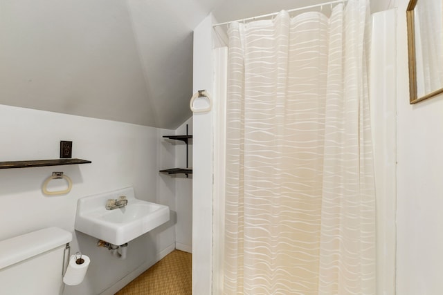 bathroom featuring lofted ceiling, toilet, and a sink