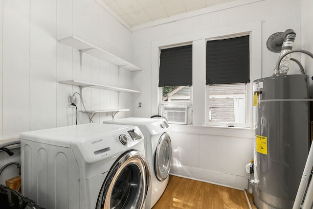 washroom with a decorative wall, wood finished floors, washer and clothes dryer, water heater, and laundry area
