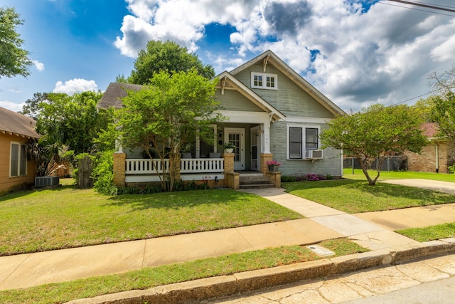 craftsman inspired home with covered porch, a front yard, and cooling unit