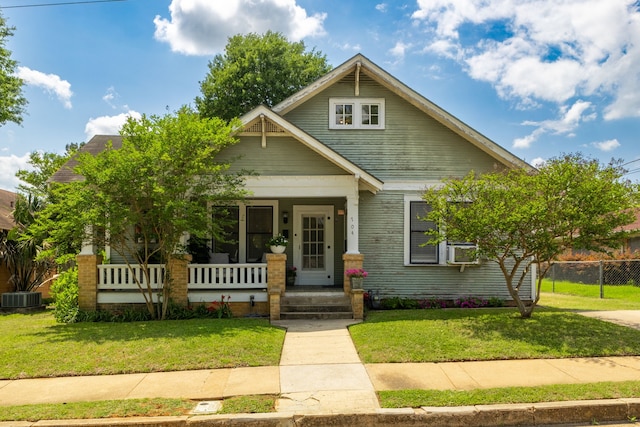 craftsman-style home with central air condition unit, a front lawn, covered porch, and fence