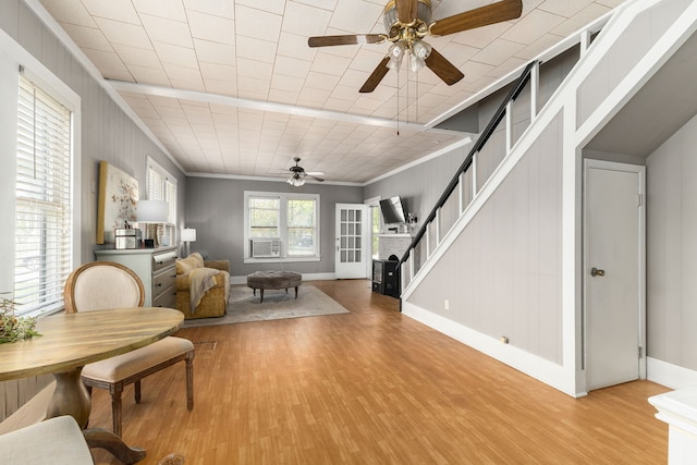 interior space with baseboards, wood finished floors, stairs, ceiling fan, and crown molding