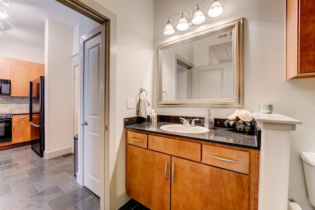 bathroom featuring backsplash, toilet, and vanity