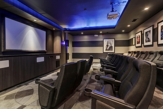 carpeted cinema room featuring a tray ceiling, visible vents, and recessed lighting