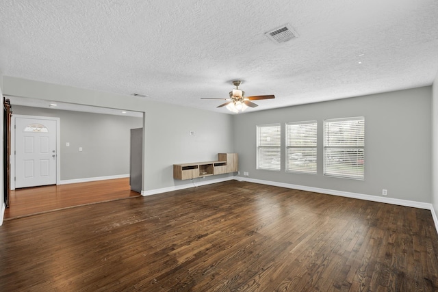 unfurnished living room with hardwood / wood-style floors, visible vents, a ceiling fan, baseboards, and a textured ceiling