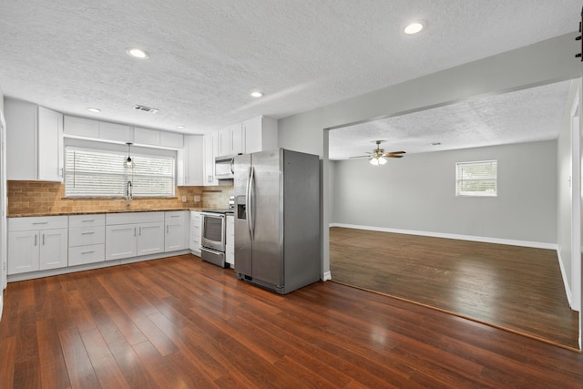 kitchen featuring a textured ceiling, ceiling fan, stainless steel appliances, dark wood-type flooring, and visible vents