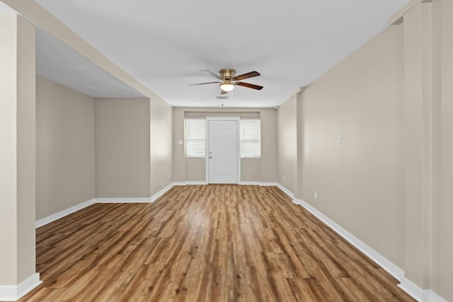 interior space with wood finished floors, visible vents, a ceiling fan, and baseboards