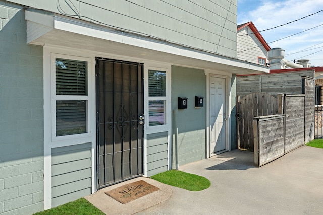 entrance to property featuring fence and concrete block siding
