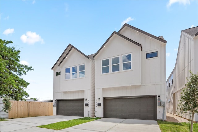 view of front of property featuring a garage, driveway, board and batten siding, and fence