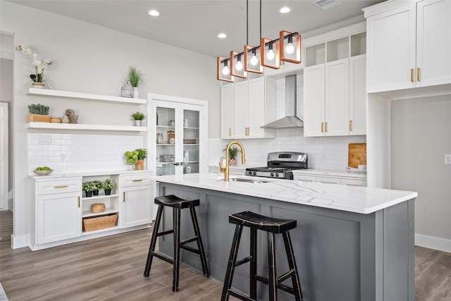 kitchen featuring wall chimney range hood, open shelves, stainless steel range oven, a sink, and recessed lighting