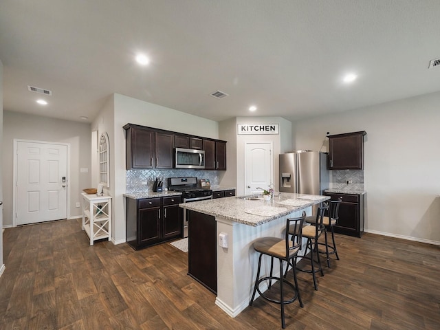 2423 Staverton Cir, Spring, TX 77373 - kitchen featuring visible vents, dark brown cabinetry, decorative backsplash, a breakfast bar, and appliances with stainless steel finishes