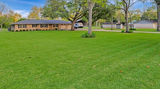 view of yard featuring driveway, a carport, and a garage