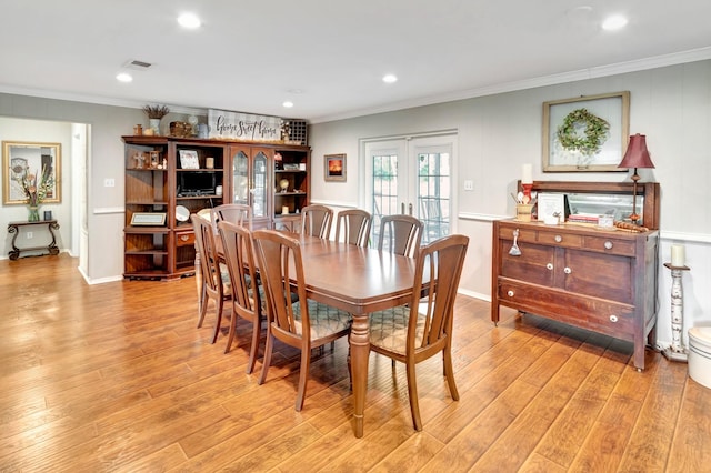 dining area featuring french doors, visible vents, light wood-style floors, and crown molding