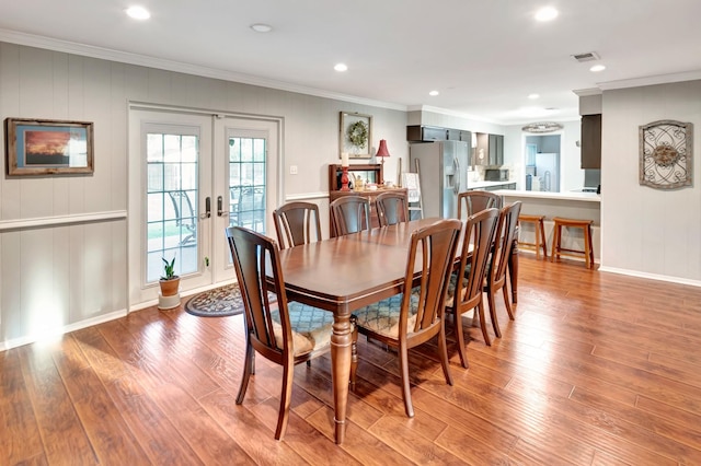 dining space with french doors, visible vents, light wood-style floors, and ornamental molding