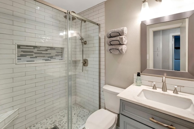 bathroom with vanity, a shower stall, and toilet
