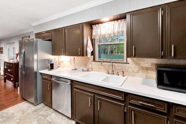 kitchen with light countertops, crown molding, stainless steel appliances, and a sink