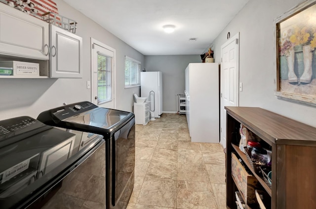washroom featuring cabinet space, stone finish floor, visible vents, and washing machine and clothes dryer