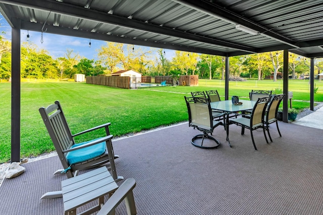view of patio with fence, an outbuilding, a storage shed, and outdoor dining space