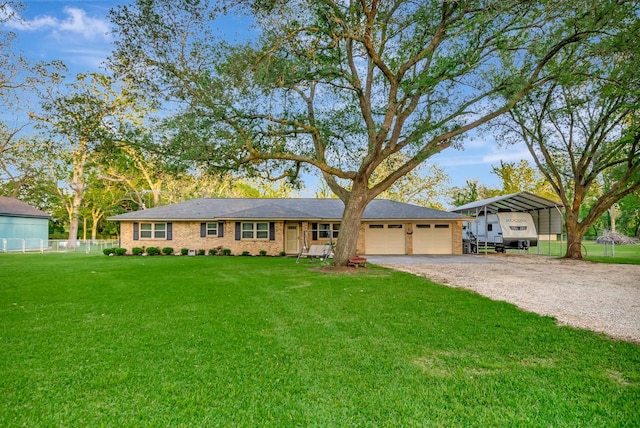 ranch-style house with driveway, fence, a front yard, a garage, and a detached carport