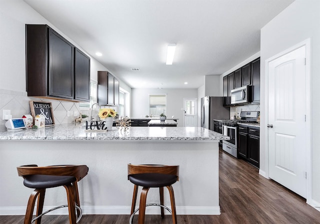 25130 Bells Canyon Dr, Porter, TX 77365 - kitchen with light stone counters, a peninsula, a kitchen breakfast bar, and stainless steel appliances