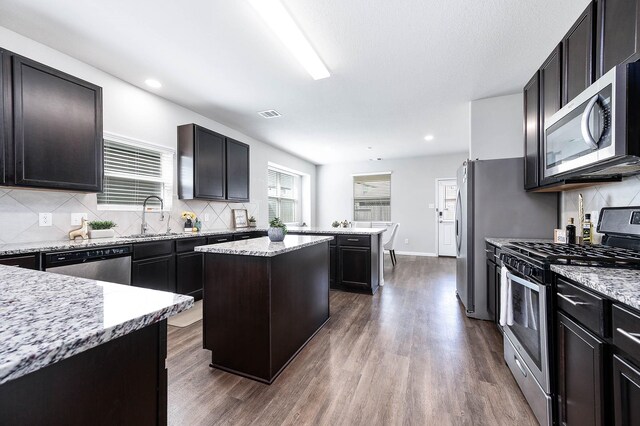 25130 Bells Canyon Dr, Porter, TX 77365 - kitchen with decorative backsplash, dark wood-type flooring, a center island, a sink, and appliances with stainless steel finishes