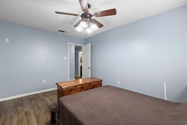 bedroom with baseboards, a ceiling fan, wood finished floors, and visible vents