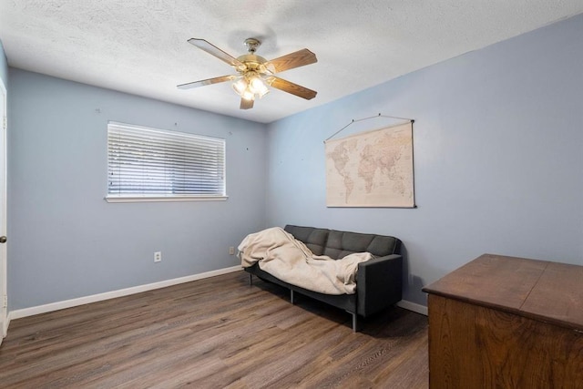sitting room with wood finished floors, a textured ceiling, a ceiling fan, and baseboards