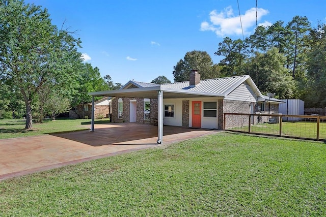 view of front of property with a chimney, a front lawn, an attached carport, fence, and metal roof